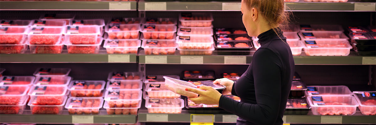 Shopper looking at beef in the grocery store.